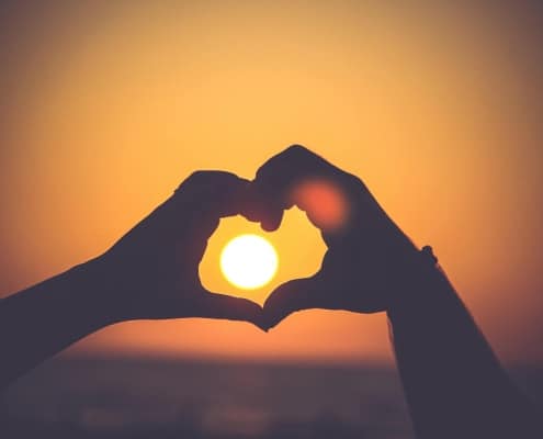 heart shape from hands around the rising sun