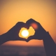 heart shape from hands around the rising sun