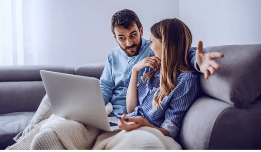 couple on couch with computer laptop online counselling. Marriage counsellor Beenleigh